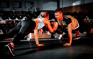 Eine Frau und ein Mann machen gemeinsame Stabilitätsübungen in einem Fitnessraum.